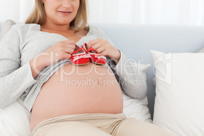 Close up of a future mom putting baby shoes on her belly