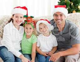 Portrait of a happy family with Christmas hats sitting on the so