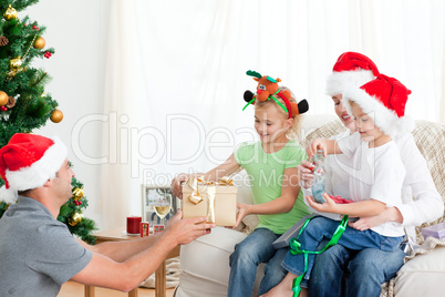 Happy father giving a present to his daughter sitting on the sof