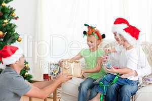 Happy father giving a present to his daughter sitting on the sof