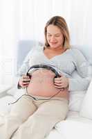 Adorable future mom putting headphones on her belly