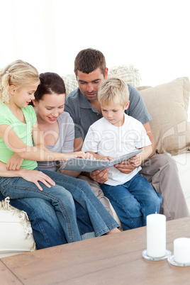 Happy family looking at a photo album sitting together in the li