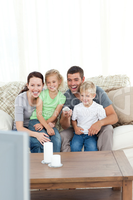 Happy family laughing while watching television sitting on the s