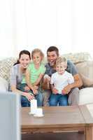 Happy family laughing while watching television sitting on the s