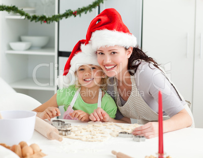 Portrait of a cute girl with her mother baking Christmas cookies