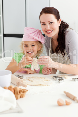 Happy girl with her mother baking little cakes