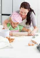 Beautiful mother and her cute daughter using a rolling pin
