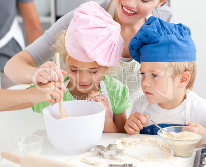 Two children and their mother stiring a preparation for cookies