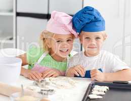 Portrait of two adorable children baking in the kitchen