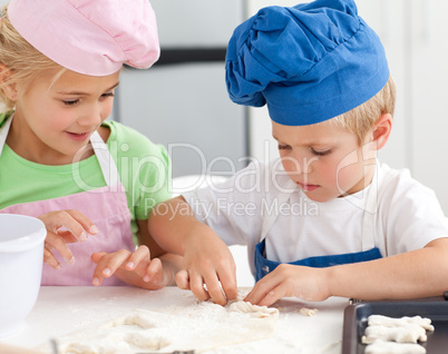 Young brother and sister kneading a dough to make cakes