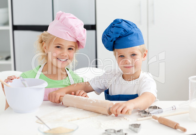 Happy brother and sister preparing a dough standing in the kitch