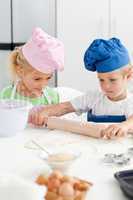 Little girl looking at her serious brother using a rolling pin