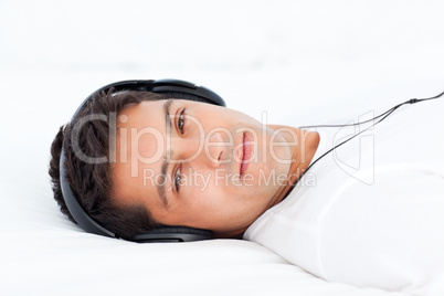 Charismatic man listening music lying on his bed