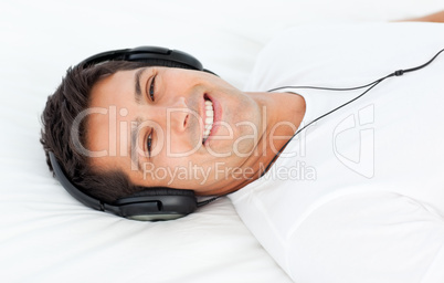 Handsome man listening to the music lying on his bed