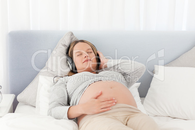 Relaxed future mom listening to the music on a bed