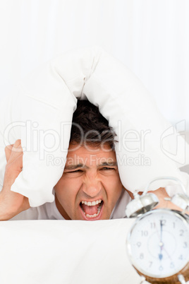 Unhappy man screaming while his alarm clock ringing