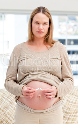 Serious future mom breaking a cigarette at home