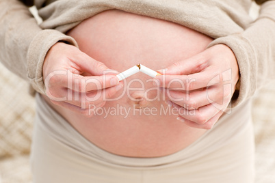 Close up of an attentive pregnant woman breaking a cigarette