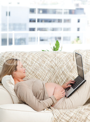 Relaxed pregnant woman using her laptop on the sofa Relaxed pregnant woman using her laptop on the sofa