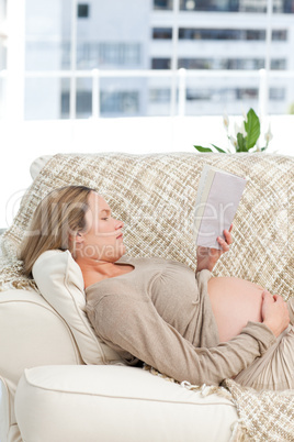 Portrait of a future mom reading a book lying