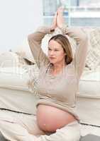 Blond pregnant woman doing yoga exercises on the floor