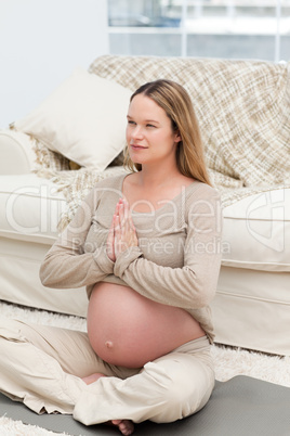 Focused future mother doing yoga exercises on the floor