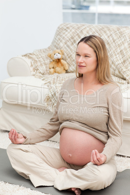 Serious future mother doing yoga on the floor