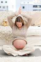 Pregnant woman doing yoga on the floor of her living-room