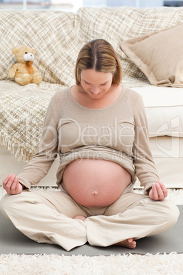 Caucasian pregnant woman doing yoga on the floor