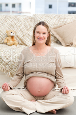 Beautiful pregnant woman doing yoga sitting on the floo