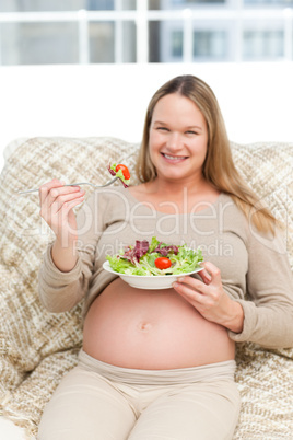 Cheerful pregnant woman eating vegetables