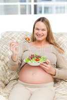 Cheerful pregnant woman eating vegetables