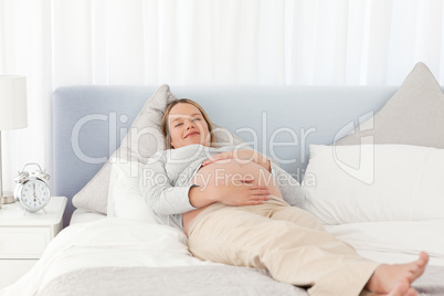 Smiling pregnant woman relaxing on a bed