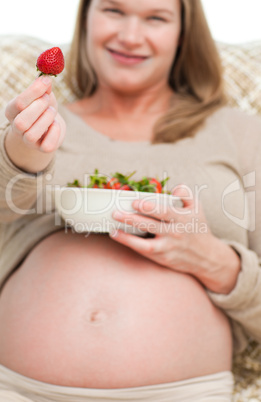Close up of a woman showing a strawberry to the camera