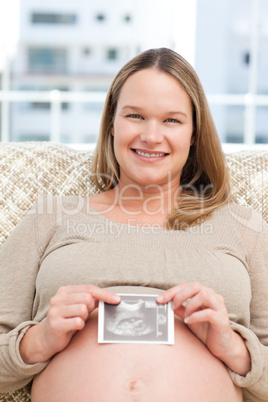 Smiling future mom showing an echography to the camera