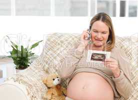 Future mom looking at an echography while phoning