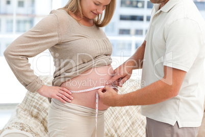 Lovely couple measuring the waist of the pregnant wife