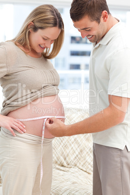 Attentive man measuring his pregnant wife's waist