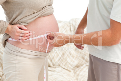 Close up of a man measuring his wife's belly