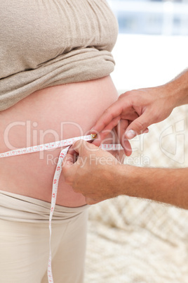 Close up of a man measuring his pregnant wife's belly