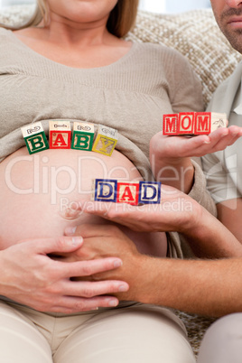 Close up of future parents holding cubes forming the words mom ,