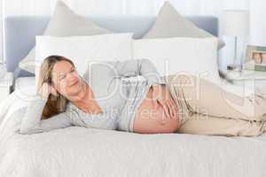 Pensive future mom lying on a bed
