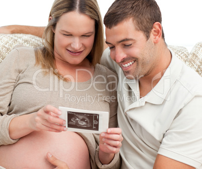 Proud future dad looking at an echography with his wife