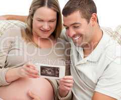 Proud future dad looking at an echography with his wife