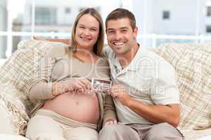 Cheerful couple of future parents holding an echography