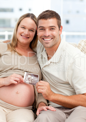 Proud future mom and dad showing an echography to the camera