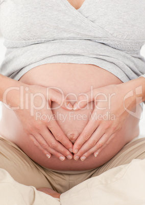 Close up of a future mom doing heart sign on her belly