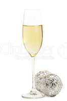 ein glas mit champagner mit zwei metallenen christbaumkugeln