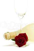 nasse rote rose mit leerem sektglas vor einer matten prosecco flasche