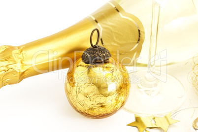 alte goldene christbaumkugel mit einem sektglas und sternen vor einer sektflasche